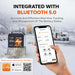Hand holding a smartphone with battery management app displayed, next to a battery and snowy landscape.